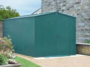 Green metal shed against a stone wall with garden elements.