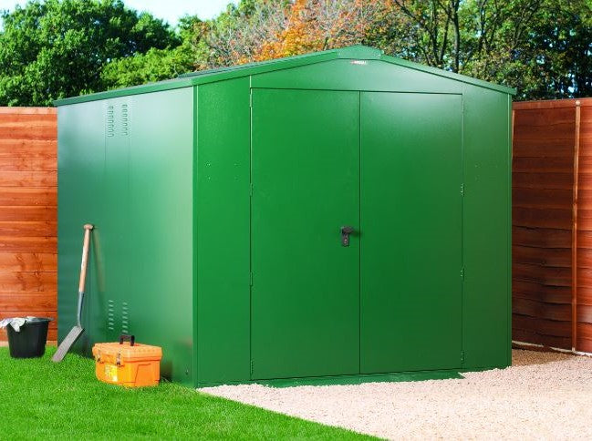 Green metal storage shed with tools on a grassy area